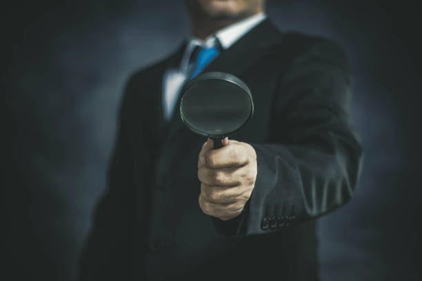 istock Businessman with Magnifying Glass on Dark Background 1148848298