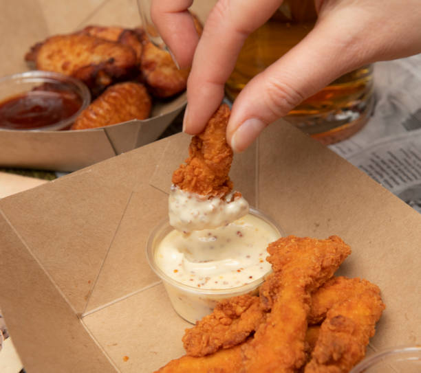 istock Hand dipping fried chicken in sauce 1148851448