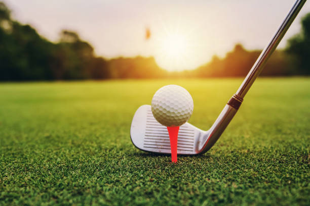 istock closeup golf club and golf ball on green grass wiht sunset 1148853477