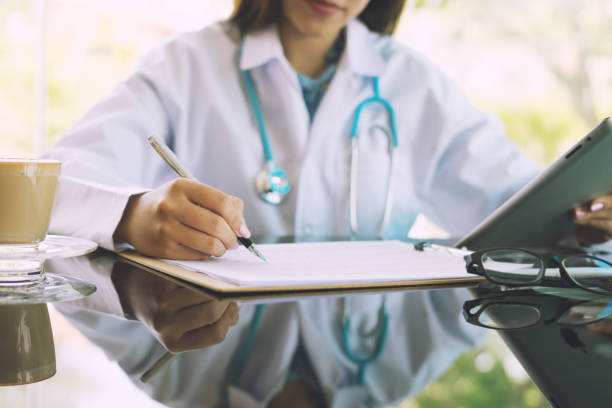 Women Doctors and patient are discussing something ,Having Consultation,Medical Pretty Doctor working in hospital writing a prescription, Healthcare and medically concept,selective focus stock photo