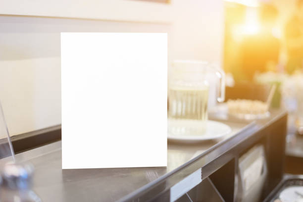 istock Mock up Menu frame on Table in Bar restaurant or coffee shop ,Stand for booklets with white sheets of paper acrylic tent card on cafeteria ,barista preparing cup of coffee for customer in background. 1148853512