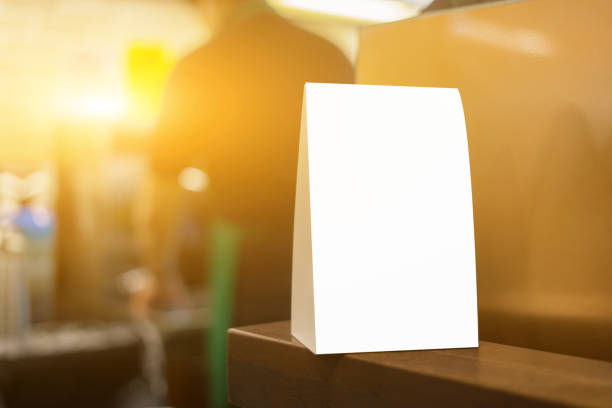 istock Mock up Menu frame on Table in Bar restaurant or coffee shop ,Stand for booklets with white sheets of paper acrylic tent card on cafeteria ,barista preparing cup of coffee for customer in background. 1148853513