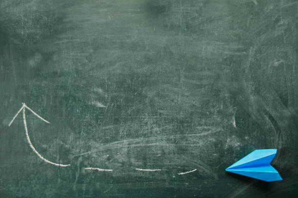 istock blue paper plane on blackboard and arrow with chalk 1148857103