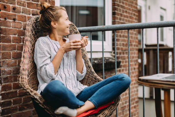 giovane donna che beve caffè a casa - balcony women patio coffee foto e immagini stock