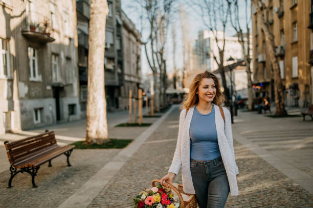 istock Young walking city streets with flower bouquet 1148861044