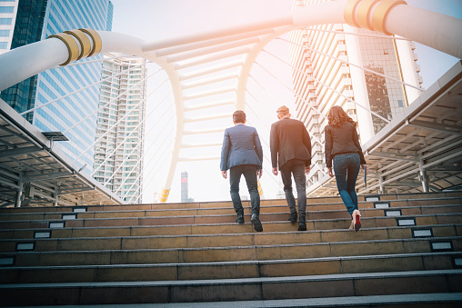 Rear view of business team climbing stairs go to a city. Business concept