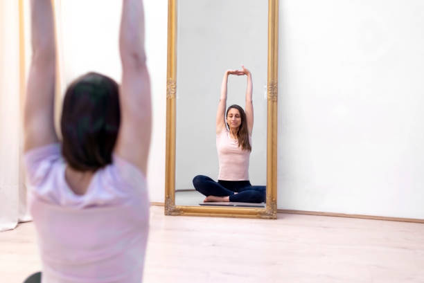 Young slim woman practices yoga at home