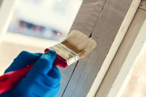 istock A gloved hand paints a window frame. Repair in the house. Services painter 1148864432