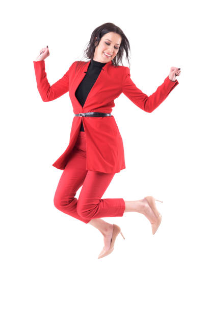 Cheerful young business woman in red dress jumping in mid air looking down Cheerful young business woman in red dress jumping in mid air looking down. Full body isolated on white background. 'formal dress' stock pictures, royalty-free photos & images