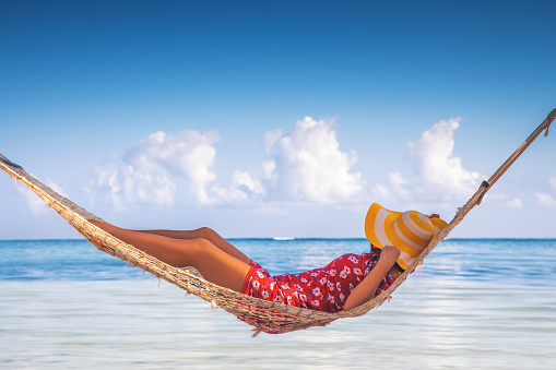Girl relaxing in a hammock on tropical island beach. Summer vacation in Punta Cana, Dominican Republic.