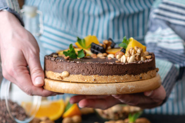 istock Hands decorated with chocolate cake orange and mint leaves with peanuts and nuts. Healthy raw desserts for vegan food 1148870569