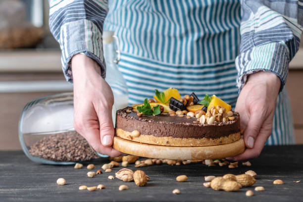 istock Hands decorated with chocolate cake orange and mint leaves with peanuts and nuts. Healthy raw desserts for vegan food 1148870635