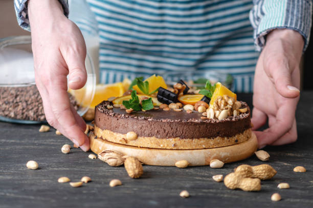 istock Hands decorated with chocolate cake orange and peanuts and nuts. Concept healthy raw desserts for vegan food 1148870637
