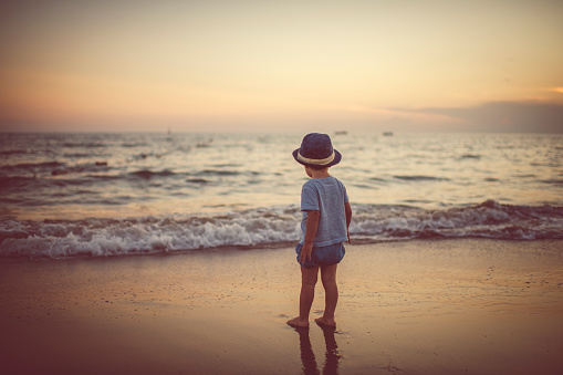 Happy child enjoying sunset near the sea