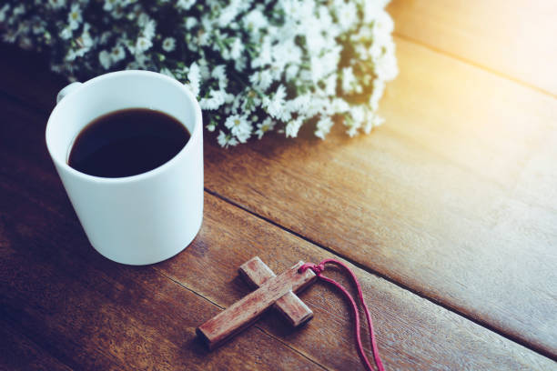 wooden cross and coffee cup the wooden cross  and a cup of cross on wooden table with flower  against 'window light, Christian background with copy space clergy stock pictures, royalty-free photos & images