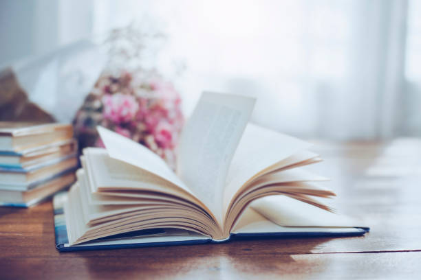 flying n page of old book with flowers on wooden background - book school desk old imagens e fotografias de stock