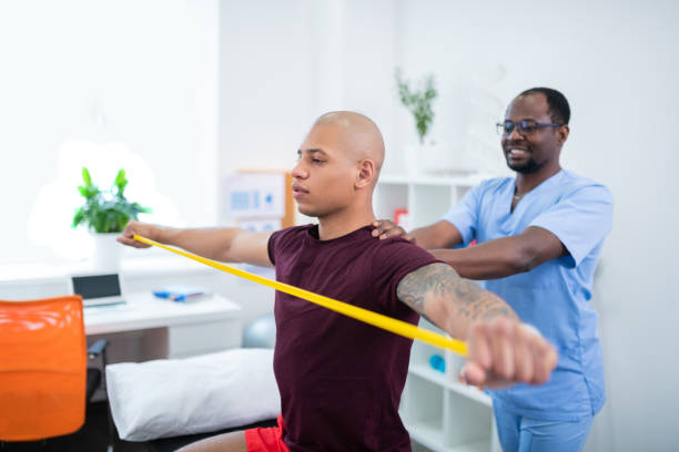 Sportsman holding ribbon stretching arms visiting therapist Holding yellow ribbon. Sportsman holding yellow ribbon while stretching arms visiting therapist sports medicine photos stock pictures, royalty-free photos & images