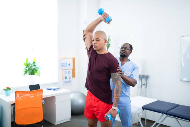 istock Sportsman holding barbells while visiting physical therapist 1148876517