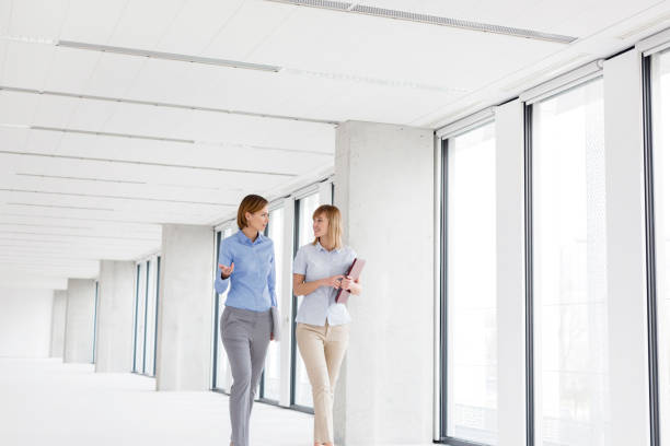 istock Businesswomen discussing while walking in empty new office 1148878400