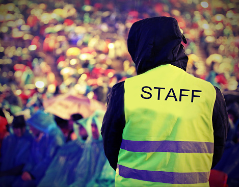 boy of Staff with high visibility jacket during live outdoor concert when it is raining with old toned effect