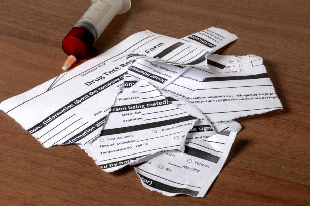 istock Torn drug test results form and syringe with blood on the table 1148878822