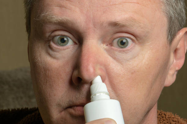 istock Sick man squirting inhaler in the nose, close-up 1148878934