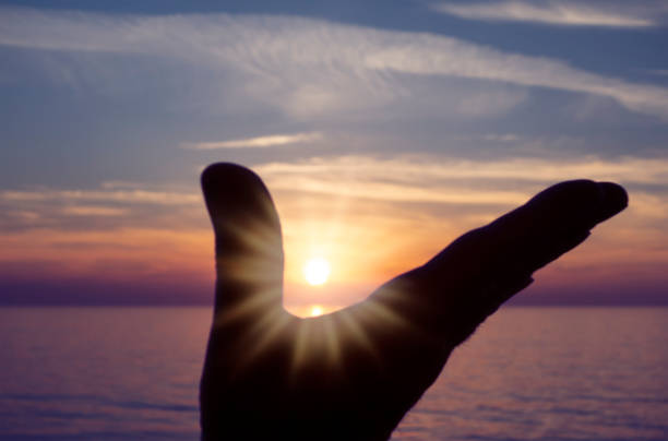 istock Silhouetted and defocused hand reaching to a sunset at sea 1148880410