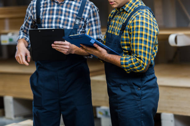 istock cropped view of two multicultural warehouse workers in uniform holding clipboards 1148880419