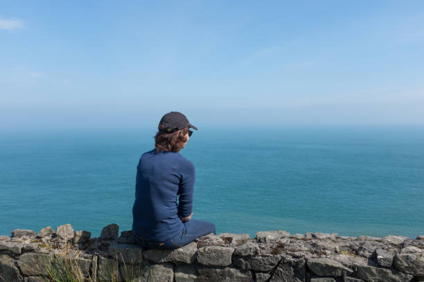 istock Woman looking at ocean back to camera, sunny day 1148880902