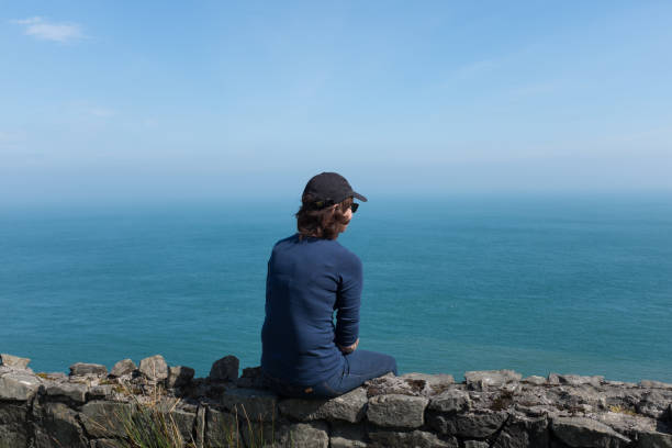 istock Woman looking at ocean back to camera, sunny day 1148881008