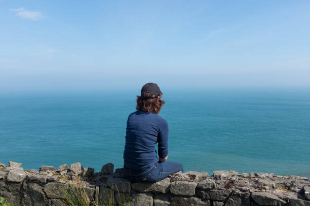 istock Woman looking at ocean back to camera, sunny day 1148881820