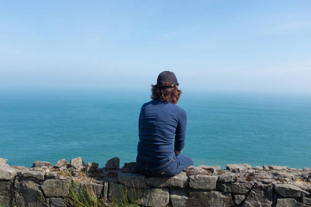 istock Woman looking at ocean back to camera, sunny day 1148882397