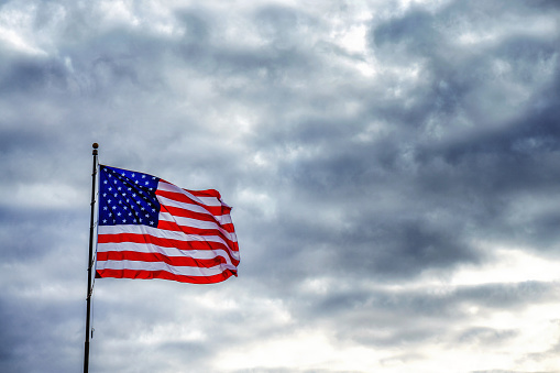 American flag flapping in dark ominous sky
