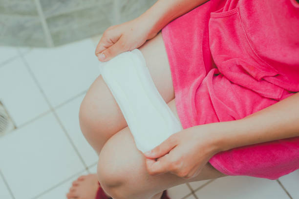 donna in bagno con un tovagliolo sanitario. la ragazza tiene un assorbente mentre è seduta in un bagno - sanitary napkin foto e immagini stock