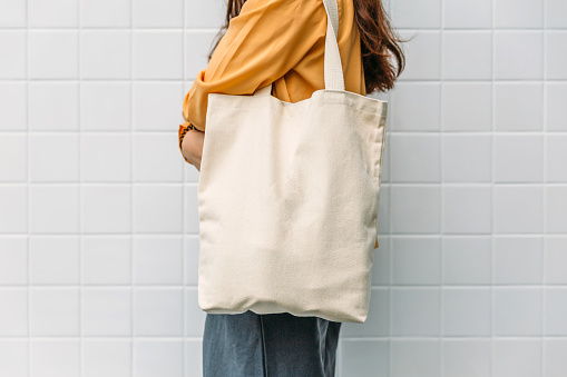 La mujer está sosteniendo tela de lona de bolsa para plantilla en blanco de maqueta. photo