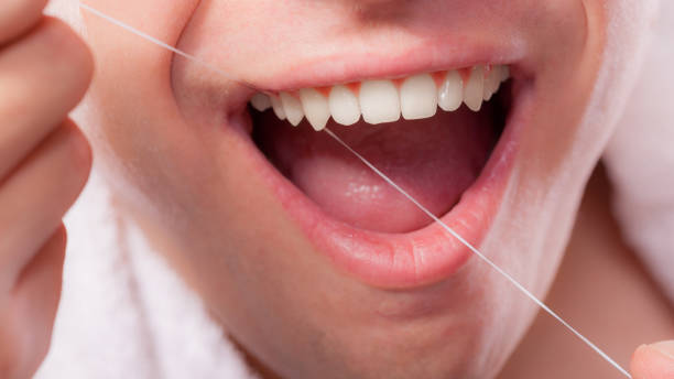 istock Young man cleaning her white teeth with dental floss 1148890960