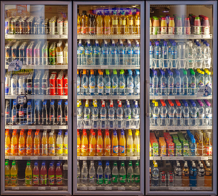 Oslo, Norway-February 22, 2011: \nIlluminated three doors vending machine / chiller cabinet, cooling shelves with a diverse range of soft drinks in a shop on the main train stationIn Oslo, Norway. Packaging to be returned for recycling for new bottles and other products