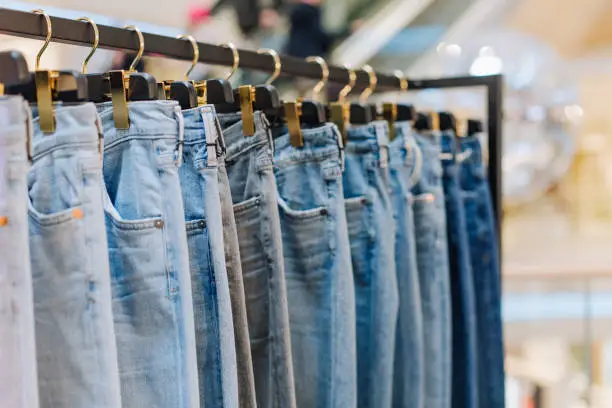 stylish jeans pants in a clothing store on the stands showcase with labels for the inscription