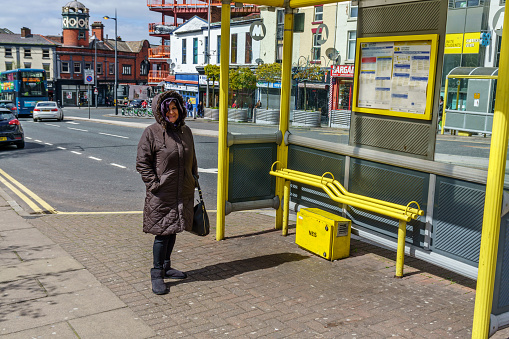 Senior Hispanic woman at bus stop in Liverpool city centre