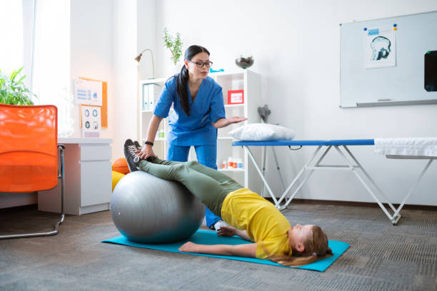 istock Professional dark-haired therapist helping little girl with stretching 1148899729