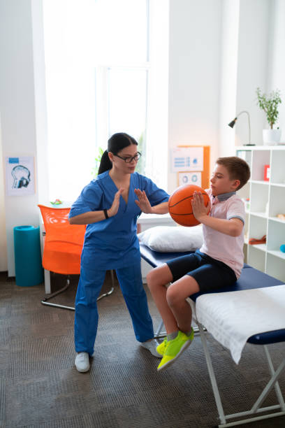 Helpful Asian physical therapist working with little boy