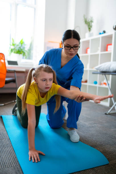 istock Diligent light-haired girl staying on blue mat and stretching body 1148899916