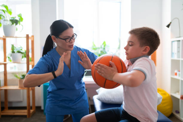 Active dark-haired nurse in blue uniform showing example Pushing hands. Active dark-haired nurse in blue uniform showing example of exercise with ball sports physical stock pictures, royalty-free photos & images