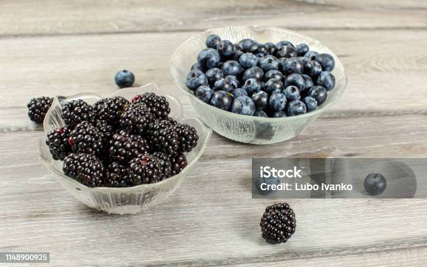 Small Glass Bowl Of Blueberries And Blackberries On Gray Wood Desk Stock Photo - Download Image Now