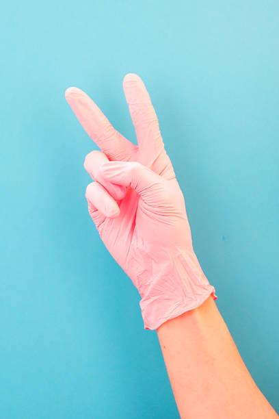 istock Pointing finger at number two, in pink gloves, on blue backdrop of. 1148901101