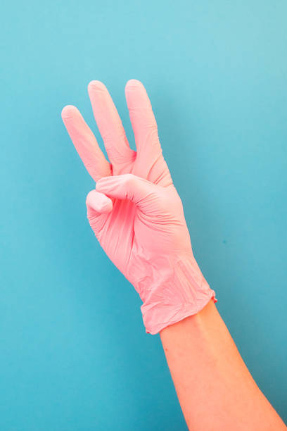 istock Pointing finger at number three, in pink gloves, on blue backdrop of. 1148901116