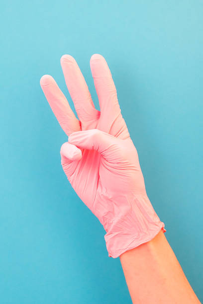 istock Pointing finger at number three, in pink gloves, on blue backdrop of. 1148901159