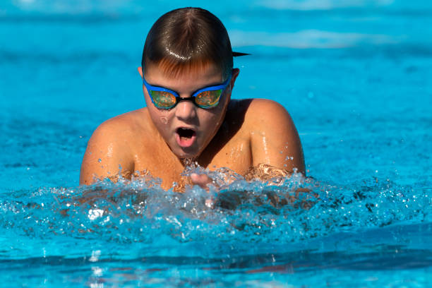 adolescente nadar braza en la piscina - braza fotografías e imágenes de stock