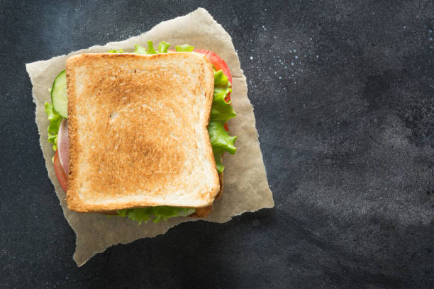 istock Sandwich with bacon, tomato, onion, salad on black background. 1148902595