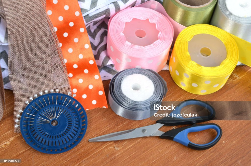 Color ribbons, scissors and pins set on wooden plank Above Stock Photo